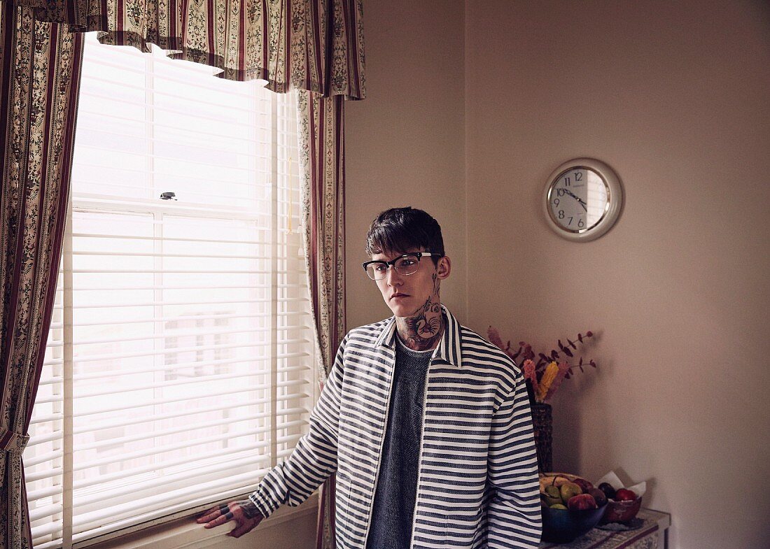 Young tattooed man in shirt and striped denim jacket