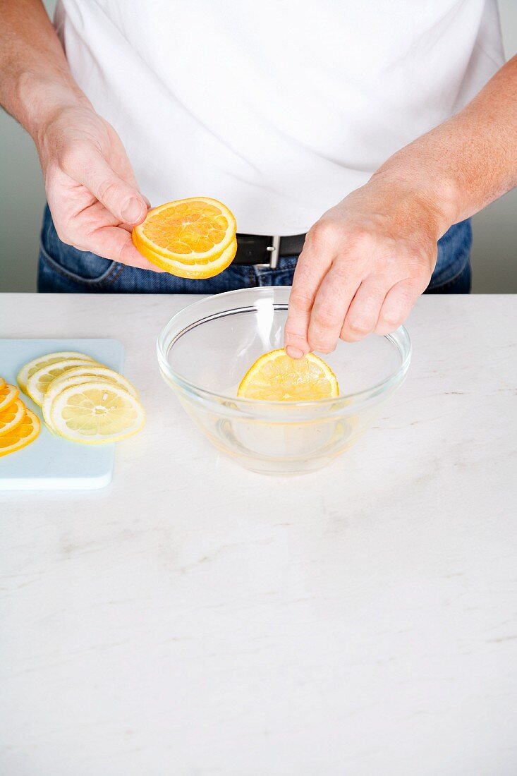 Citrus fruit slices being dipped into sugared water