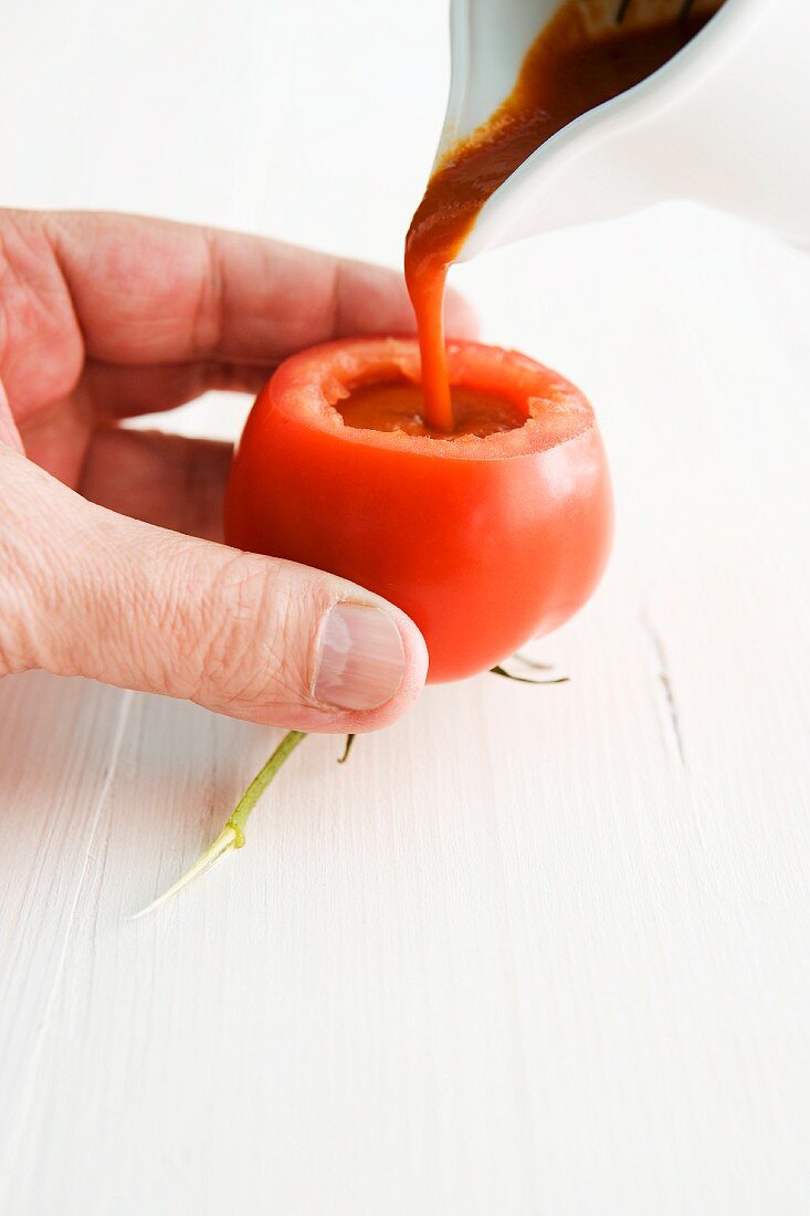 Tomato soup being poured into a hollowed out tomato