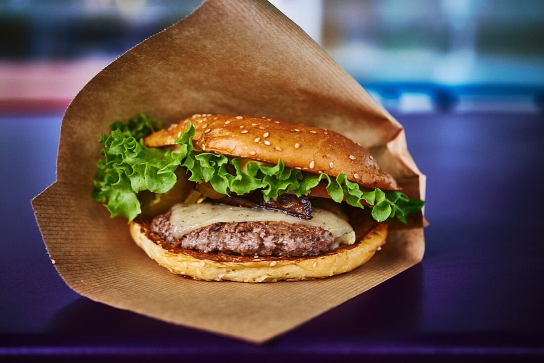 A cheeseburger with salad in a paper bag