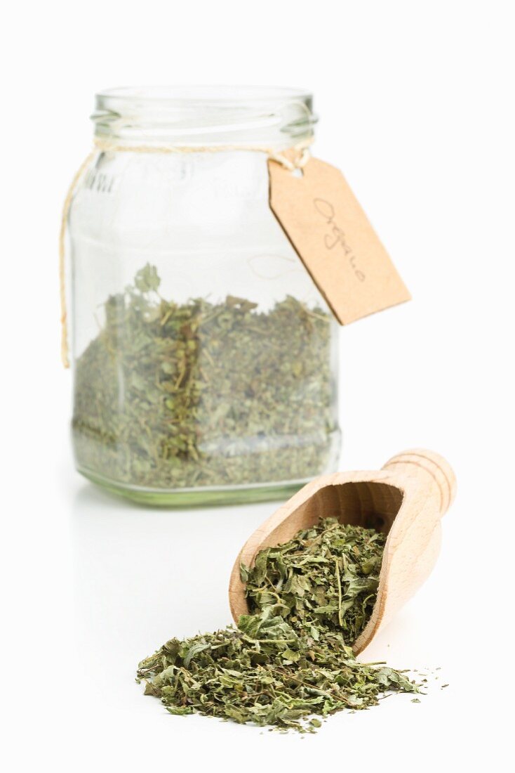 Dried oregano on a wooden scoop and in a storage jar
