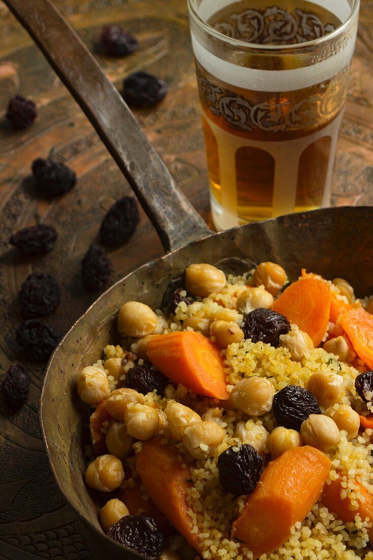 Veganes Couscous mit Korinthen, Kichererbsen und Möhren in einer Kupferpfanne