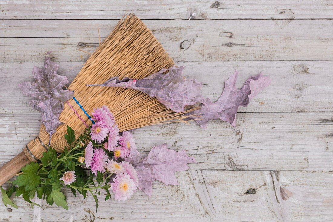 Pink chrysanthemums and autumnal oak leaves on besom broom