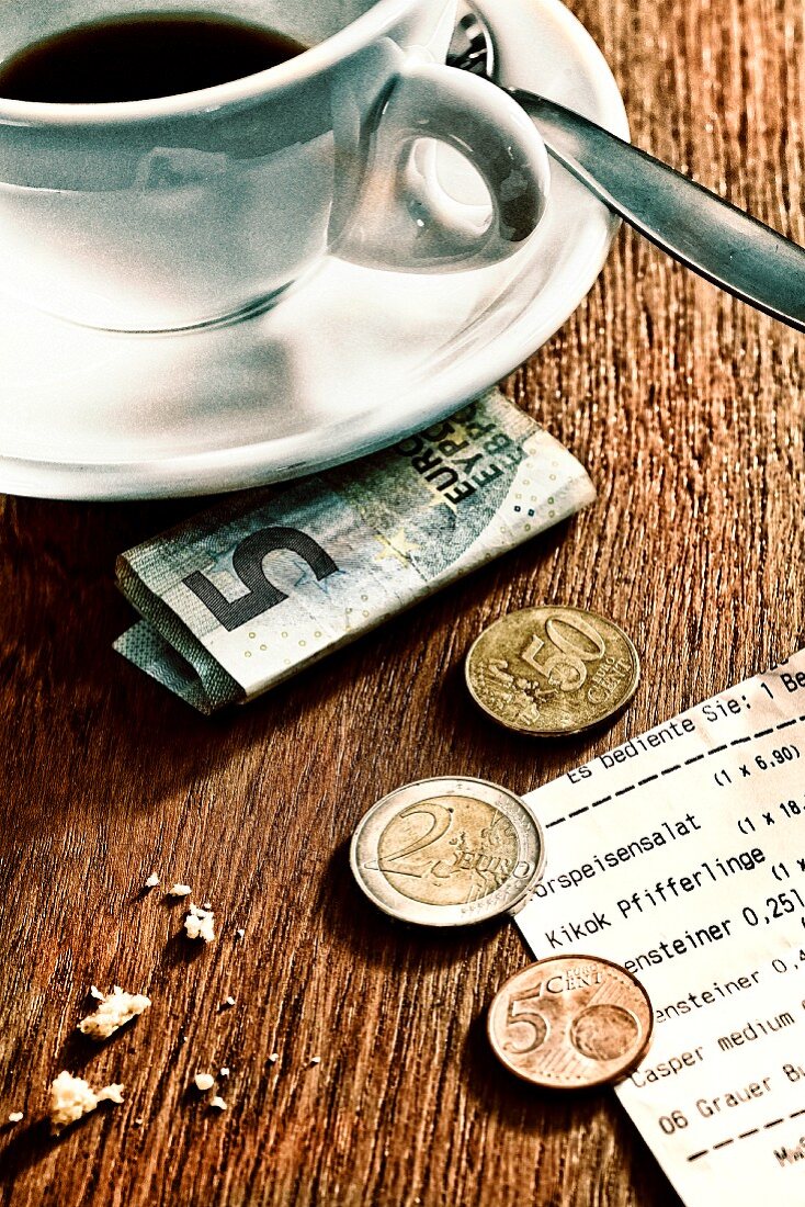 Trinkgeld und Quittung neben Kaffeetasse
