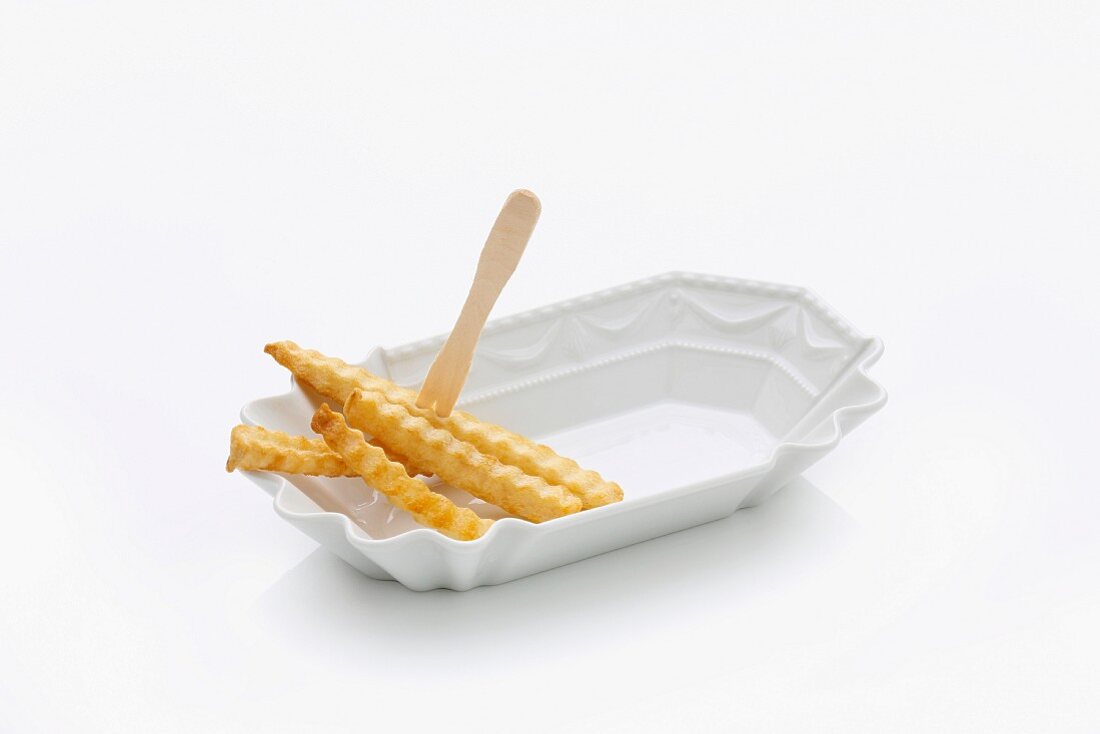 Four crinkle-cut chips with a wooden fork in a porcelain dish