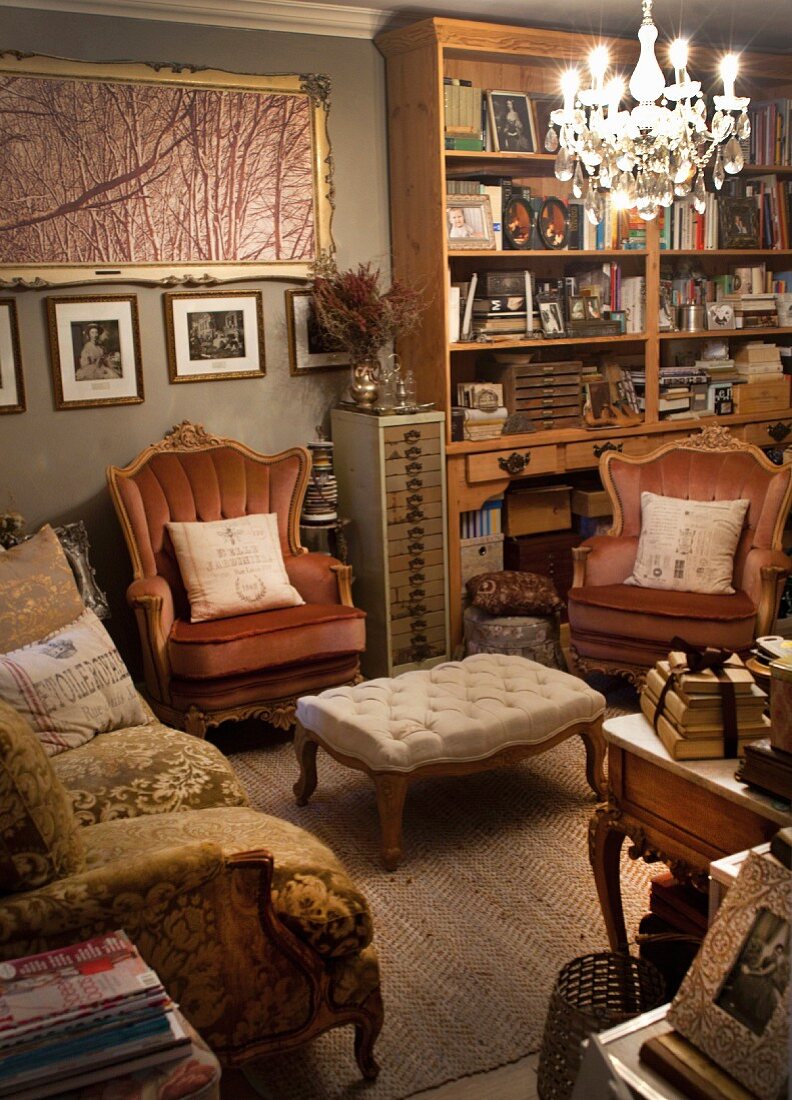 Antique-style sofa and armchairs around ottoman below chandelier in living room