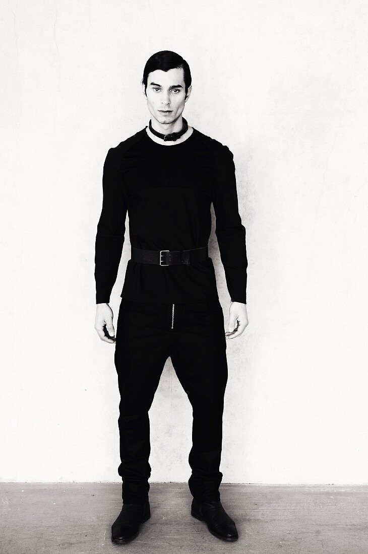 A young man wearing black clothing with a leather choker (black-and-white shot)