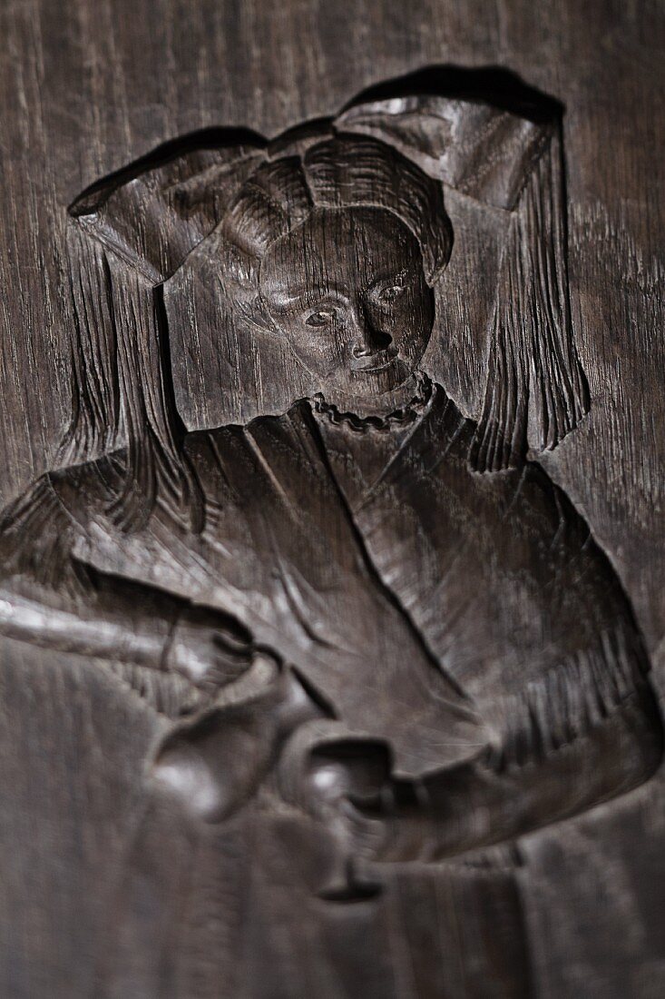 An antique wooden relief of a woman pouring wine