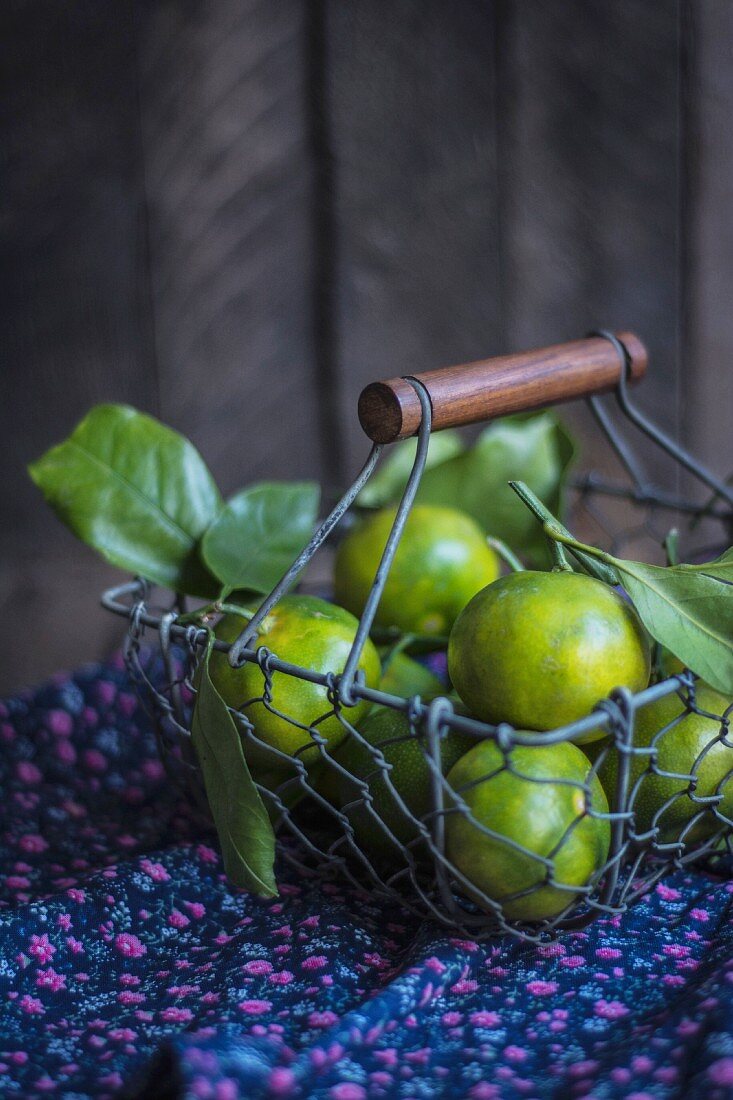 Green tangerines with leaves in a wire basket