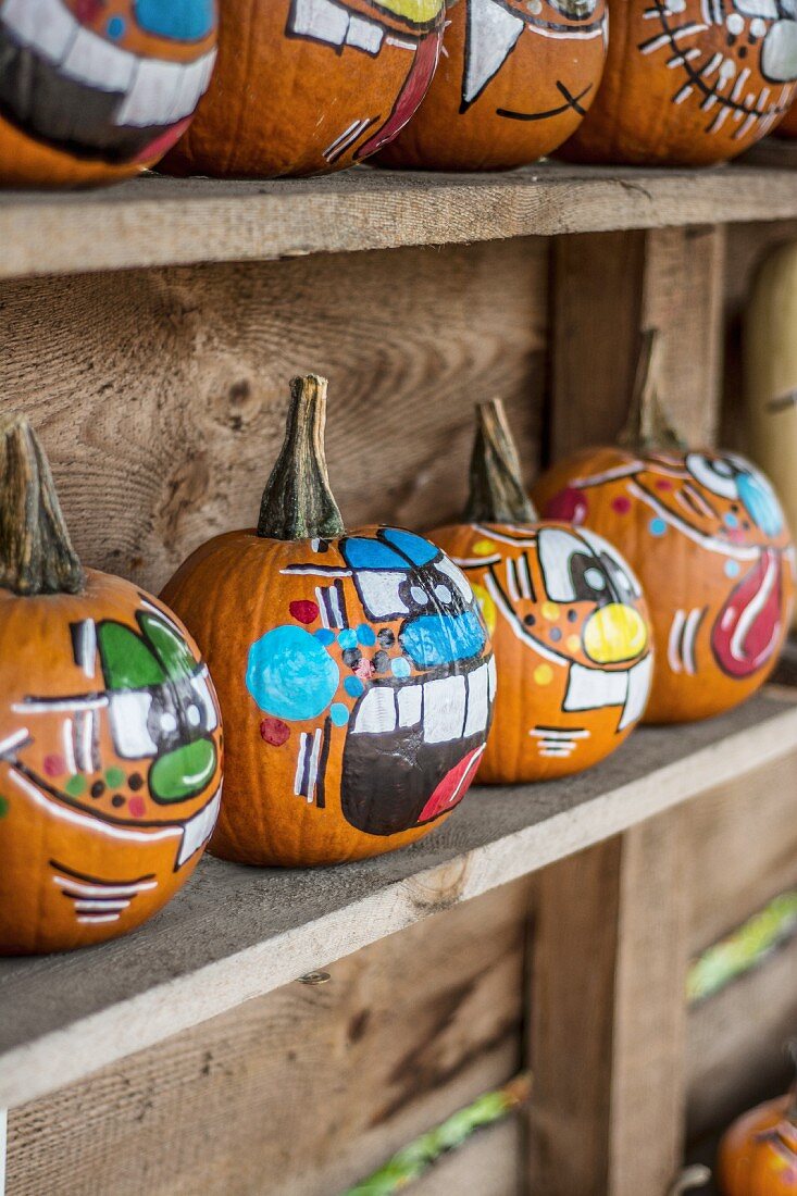 Painted Halloween pumpkins on a wooden shelf