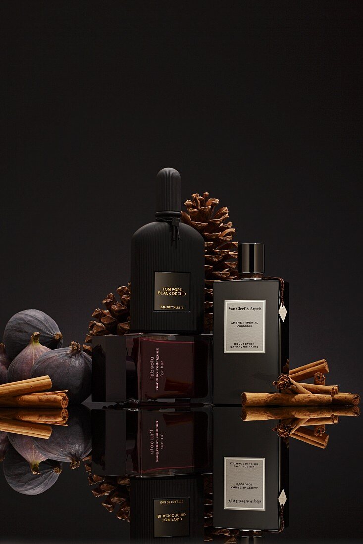 Drei dunkle Parfumflakons vor schwarzem Hintergrund (Winterdüfte)