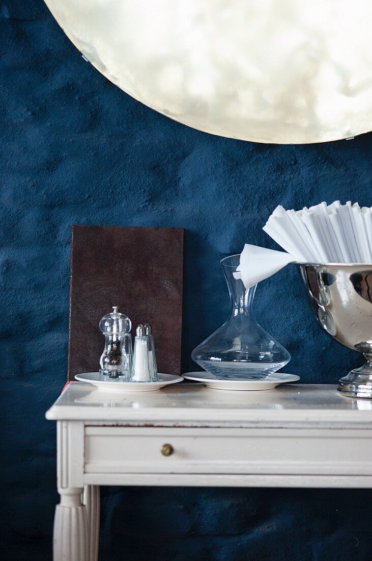 Menu, salt and pepper, carafe and napkins on console table in restaurant