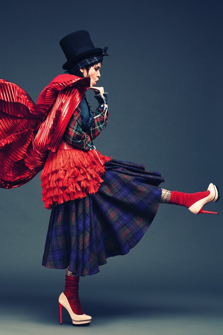 A young woman wearing a kilt and a red cape