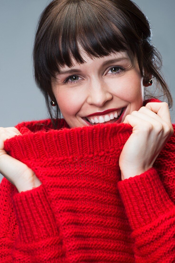 A dark-haired woman wearing a red knitted jumper