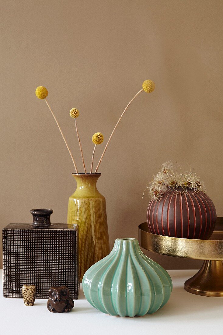 Autumnal still-life arrangement of vases, dried flowers and owl figurines