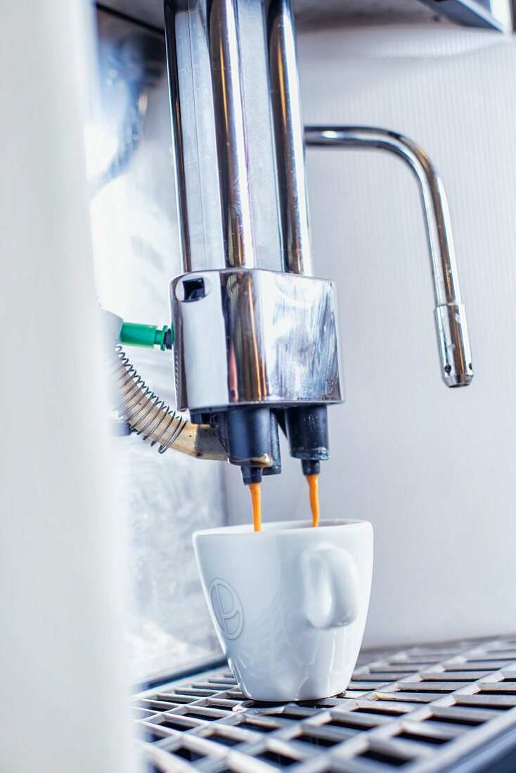 Coffee flowing from a coffee machine into a cup