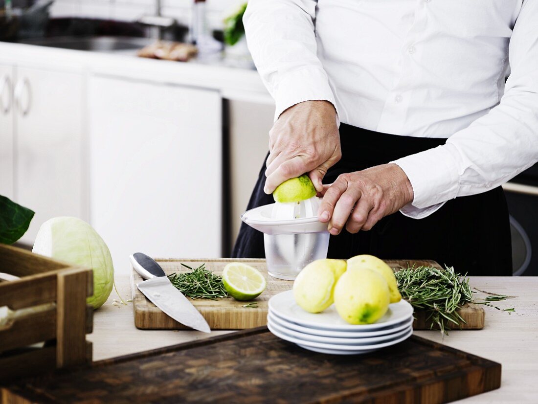 A man in a kitchen juicing lemons and limes