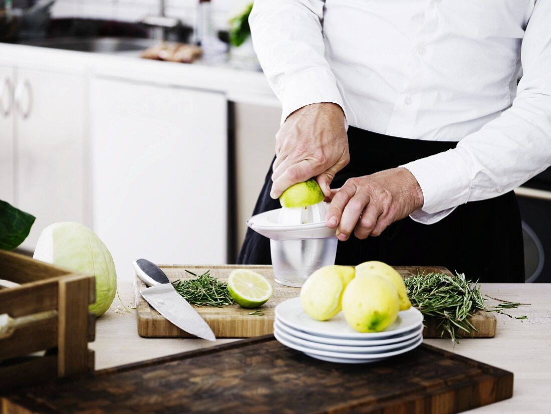 Mann in Küche presst Limetten & Zitronen mit Zitruspresse aus