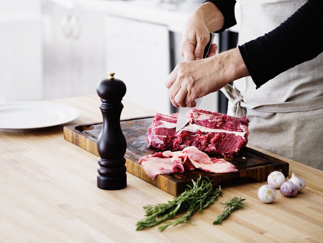 A man removing tendons and fat from a piece of beef