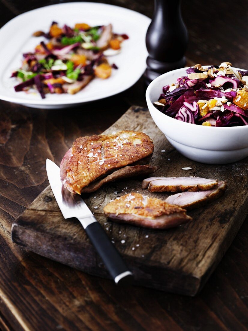 Sliced duck breast and winter red cabbage salad on a wooden board