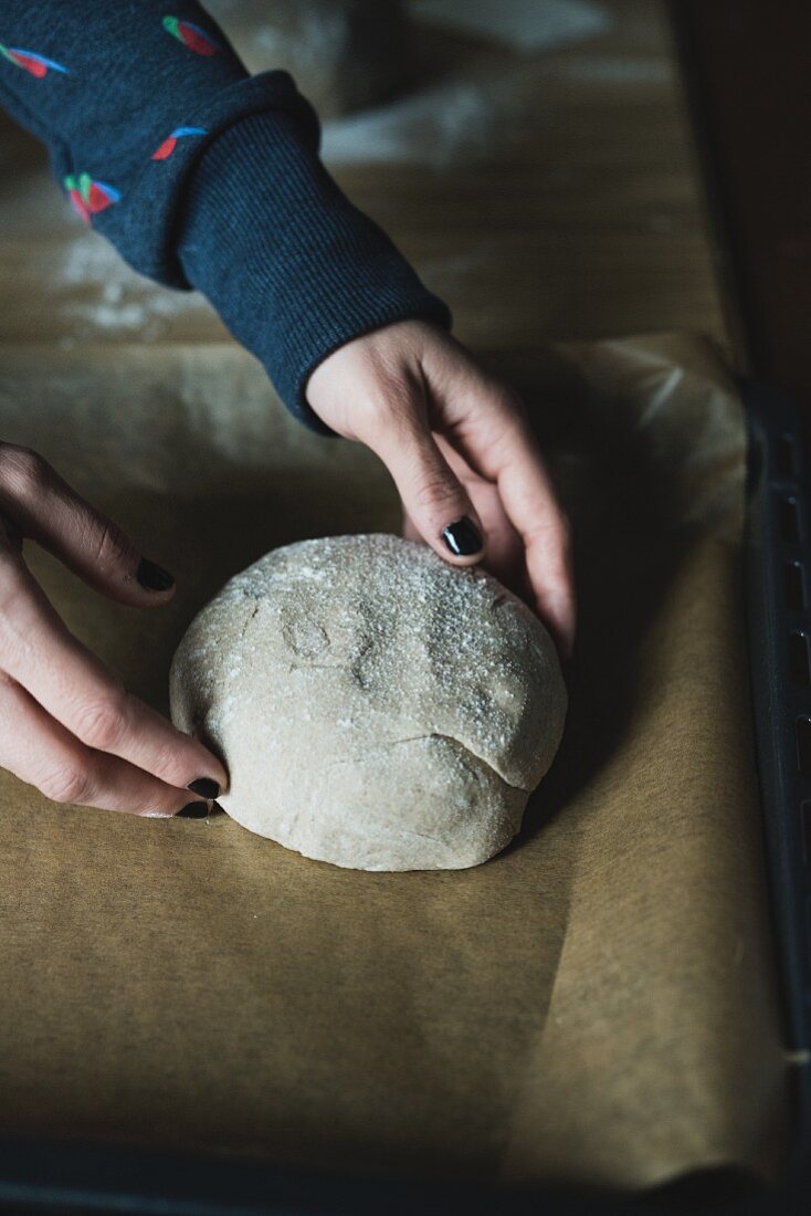 A loaf of sour dough bread being placed on a baking tray