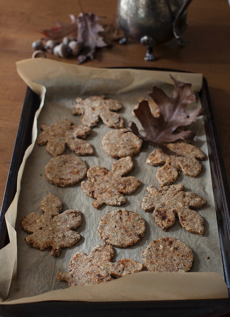 Autumnal leaf-shaped pumpkin seed and flaxseed crackers on a baking tray