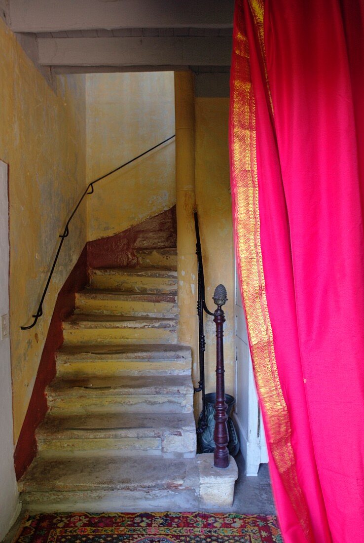 Vintage stairwell with masonry winding stairs, delicate handrail and hot pink curtain in foreground