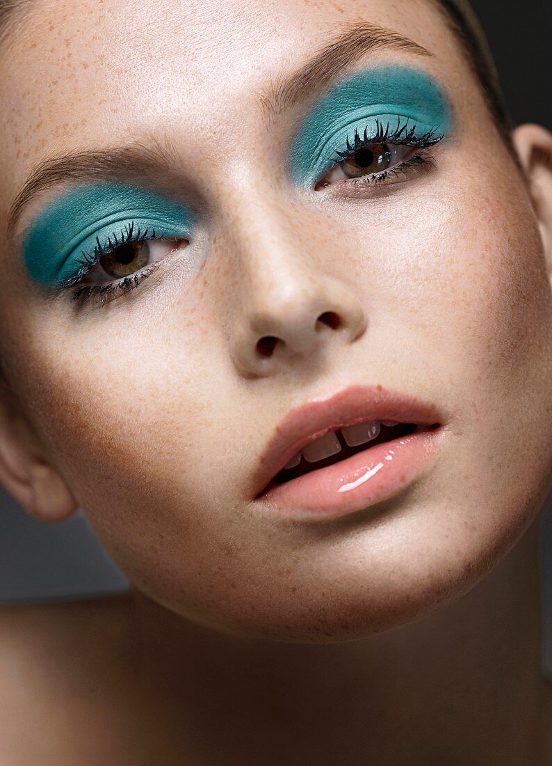 A young woman wearing blue eye shadow and nude lipstick