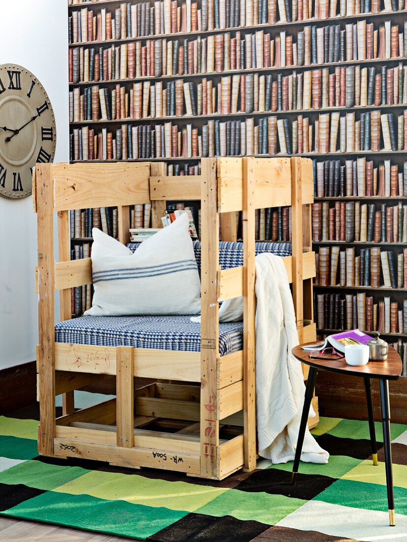 Selbstgebautes rustikales Sitzmöbel mit Polster und Kissen vor Bücherwand-Fototapete