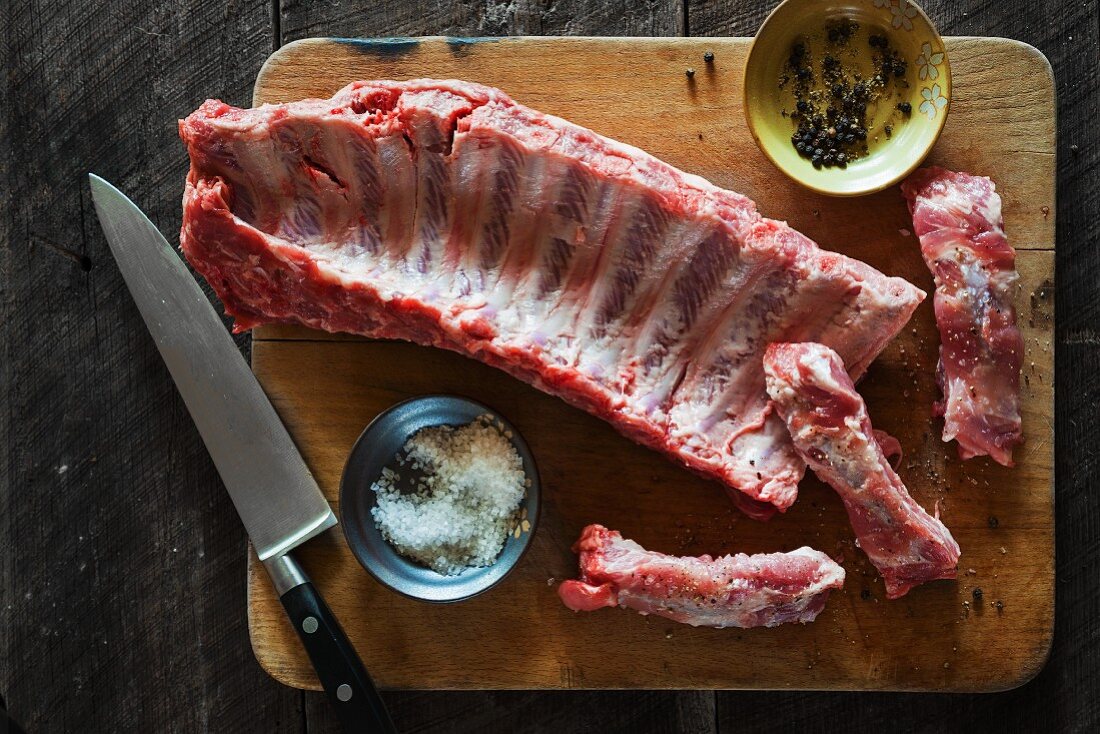 Raw pork ribs on a chopping board with salt and pepper