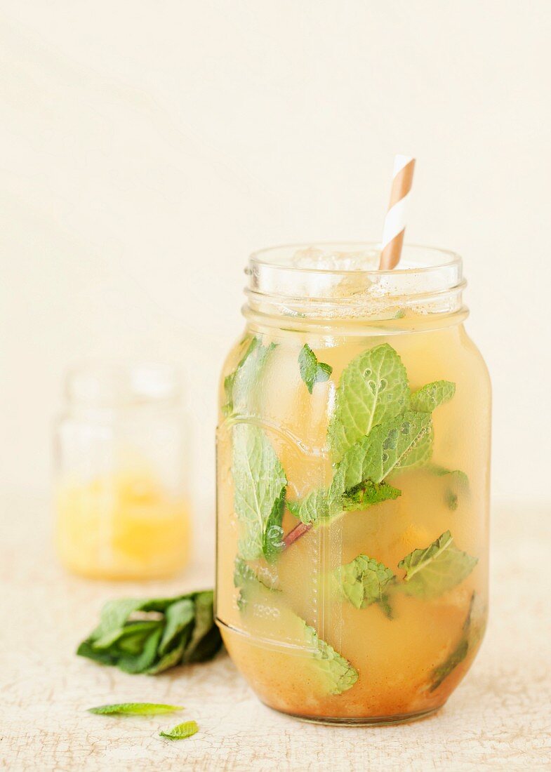 A cocktail made with bourbon, pineapple, pear, mint and cinnamon in a jam jar