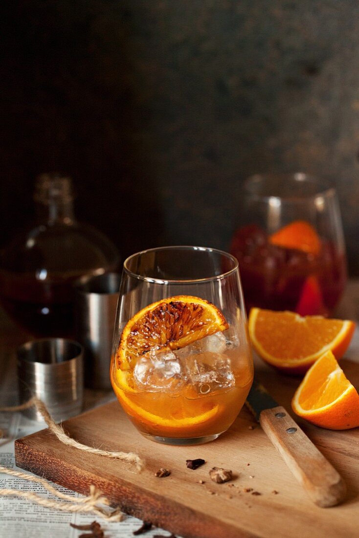 A negroni with spices and roasted oranges being made