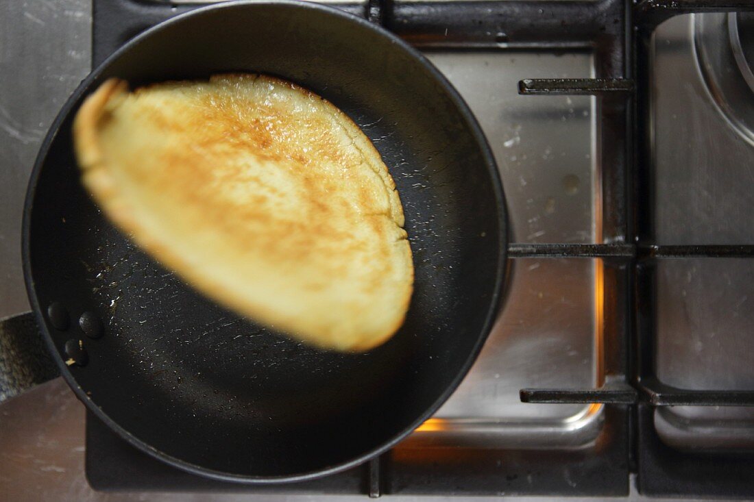 A crêpe being turned in a pan