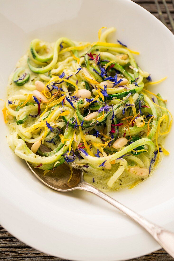 Courgette noodles in a goat's cheese and lemon sauce with pine nuts and dried flowers