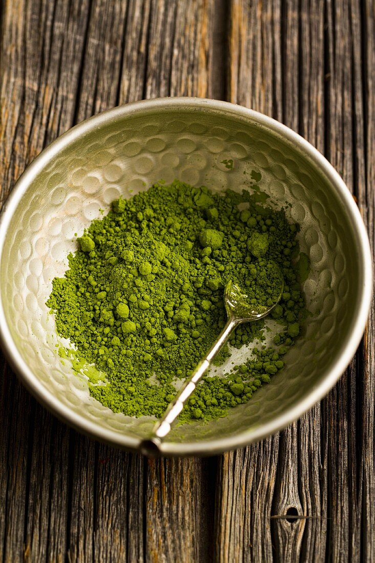 Matcha tea powder in a metal bowl with a spoon