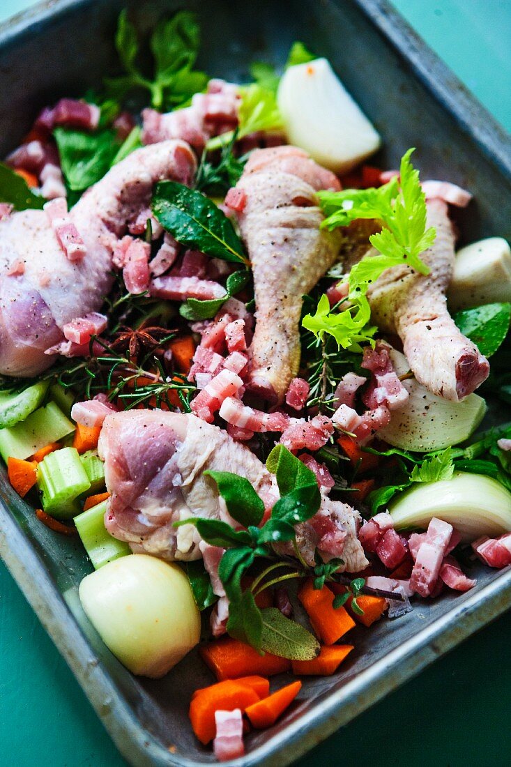 Ingredients for sauce (chicken, bacon and vegetables) in a roasting tin