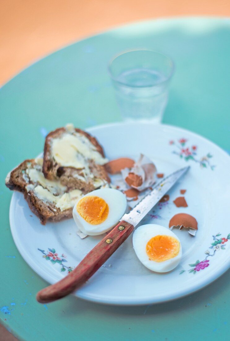 Hartgekochtes Ei und Butterbrot auf Teller