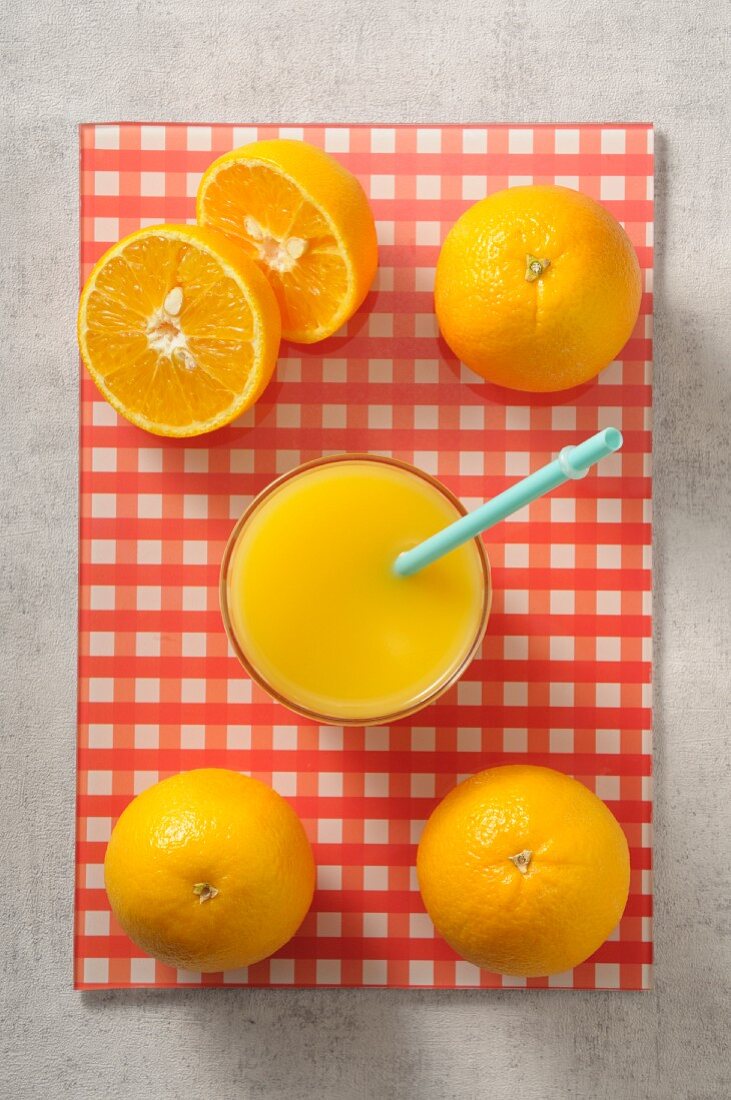 A glass of orange juice and fresh oranges