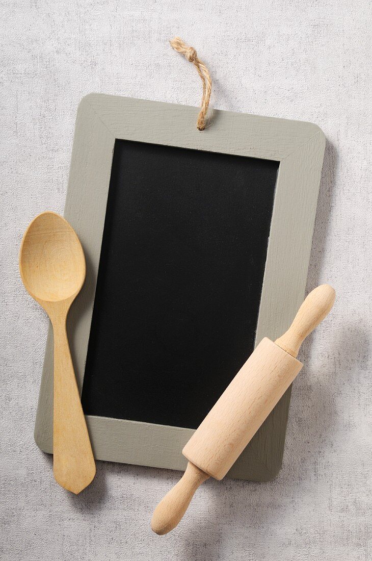A chalkboard, a wooden spoon and a rolling pin