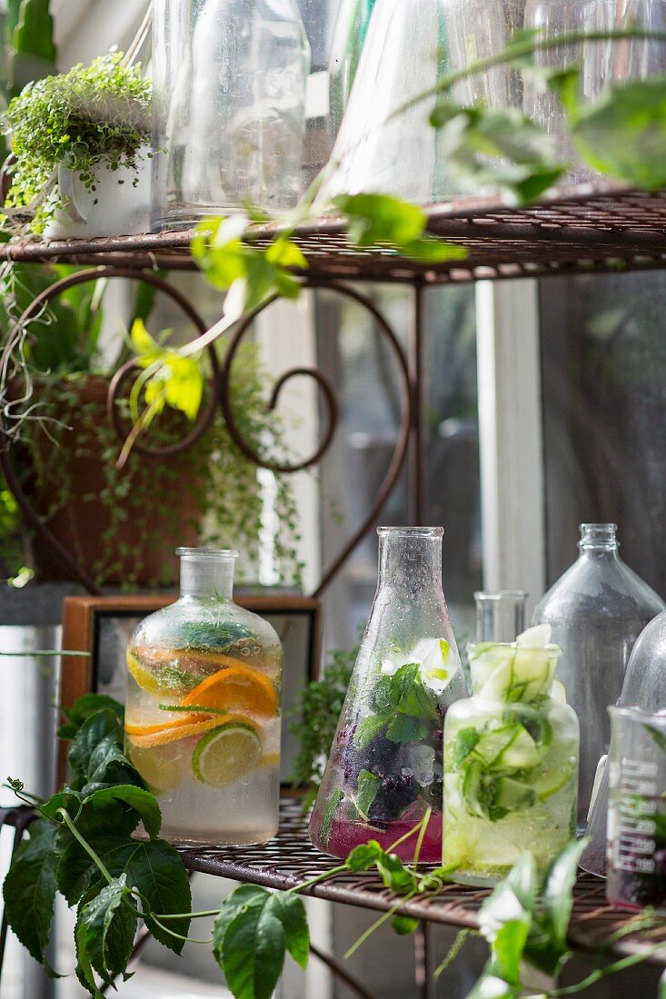 Various summer drinks with fruit, vegetables and herbs on a shelf in front of a house