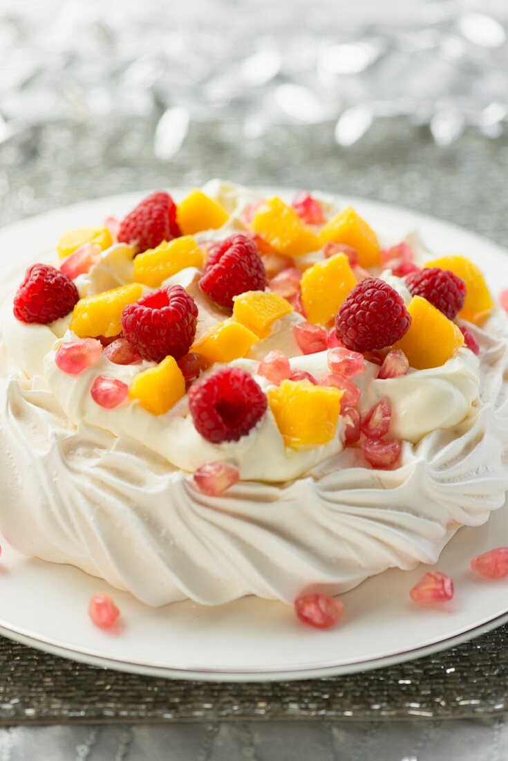 Mango and raspberry pavlova with pomegranate seeds