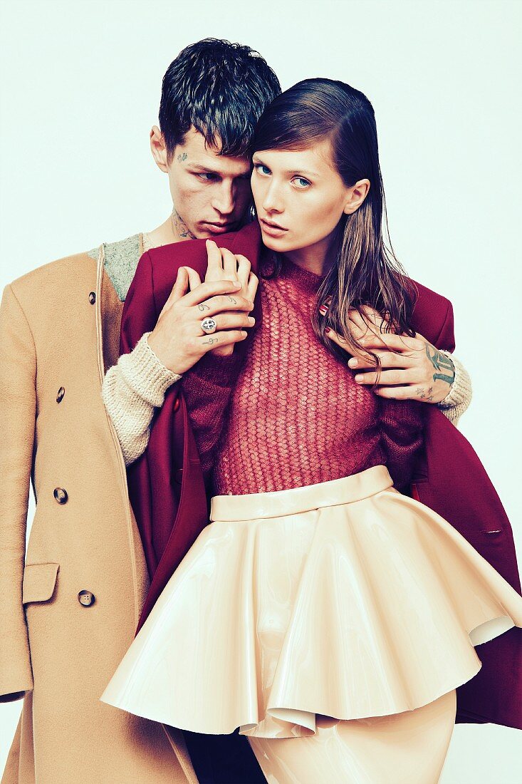 A woman wearing a knitted jumper, a jacket and a plastic skirt and a man wearing a coat