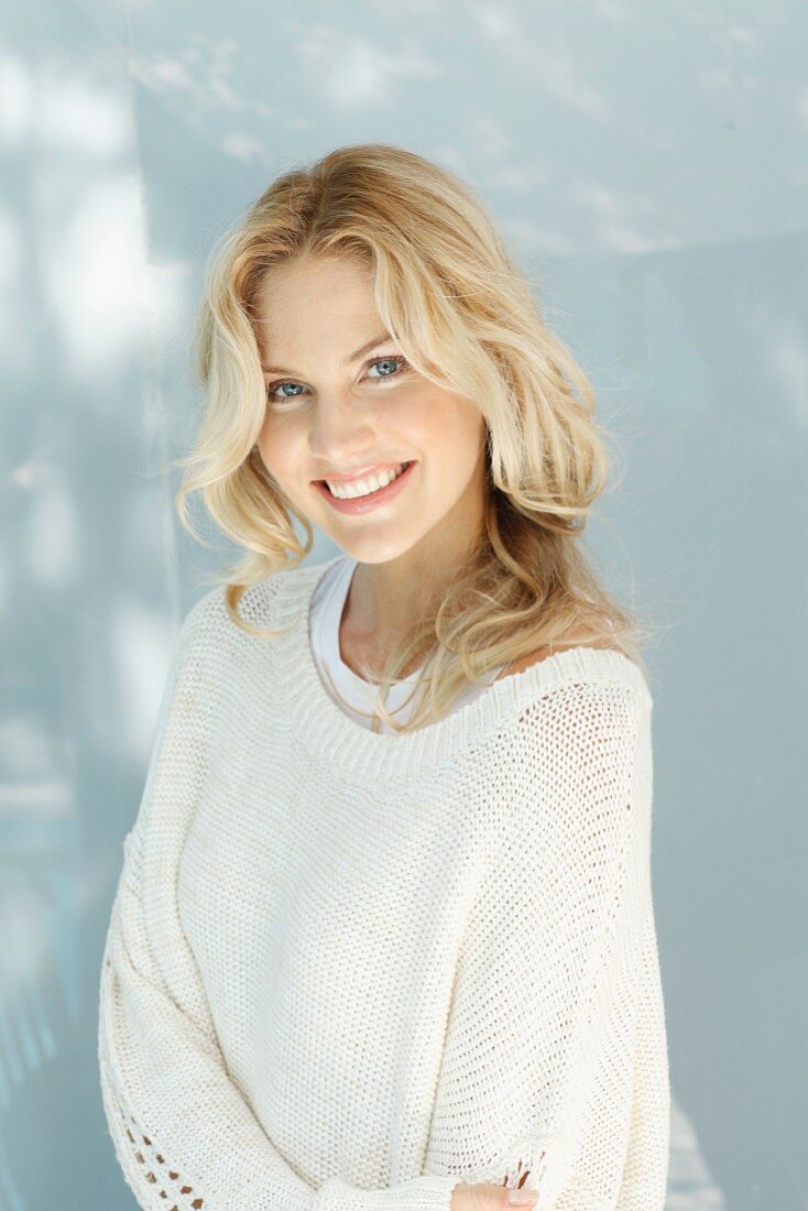 A young blonde woman wearing a natural-coloured woollen jumper