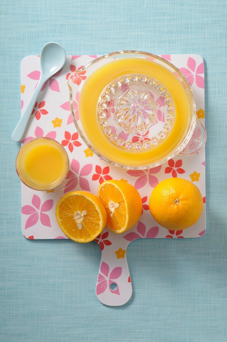 Freshly pressed orange juice, a juicer and oranges