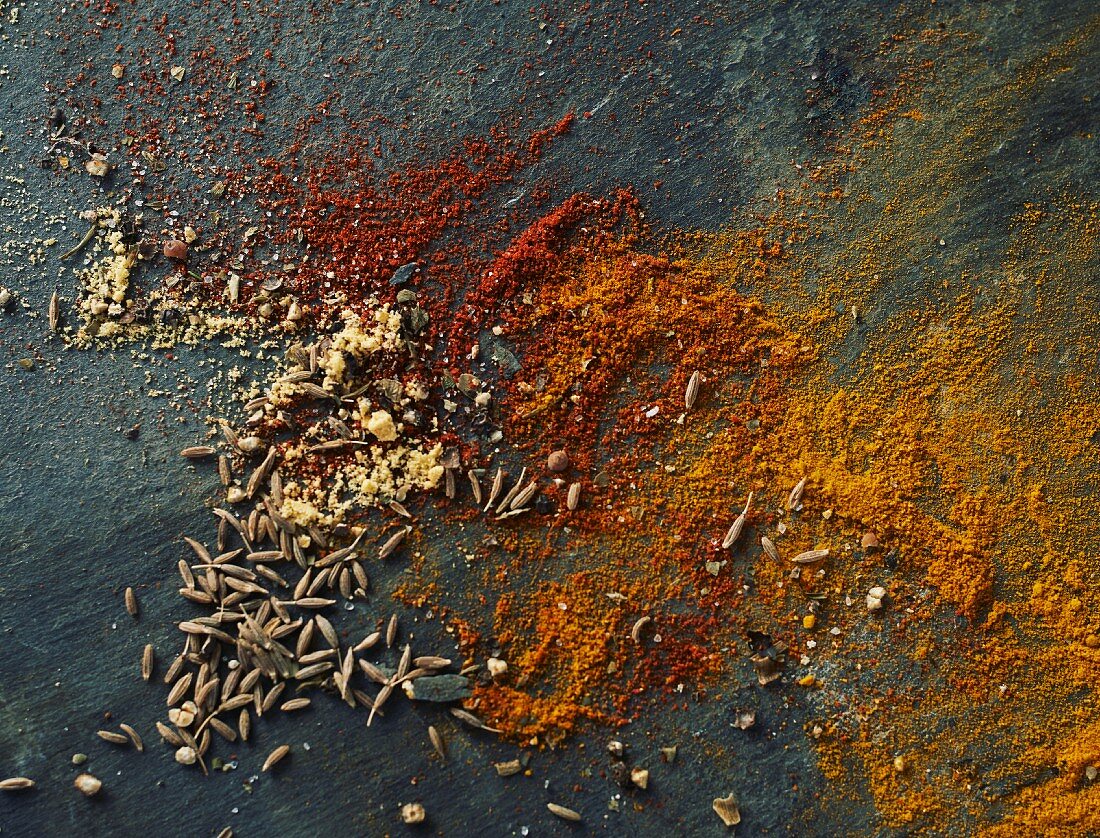 Ground paprkia, turmeric, cumin and fennel seeds on a slate platter