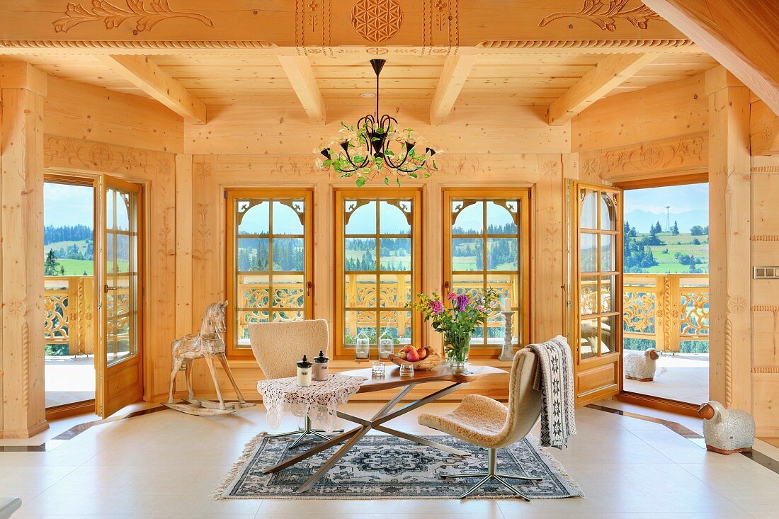 Modern chairs around delicate table in living area of solid-wood house