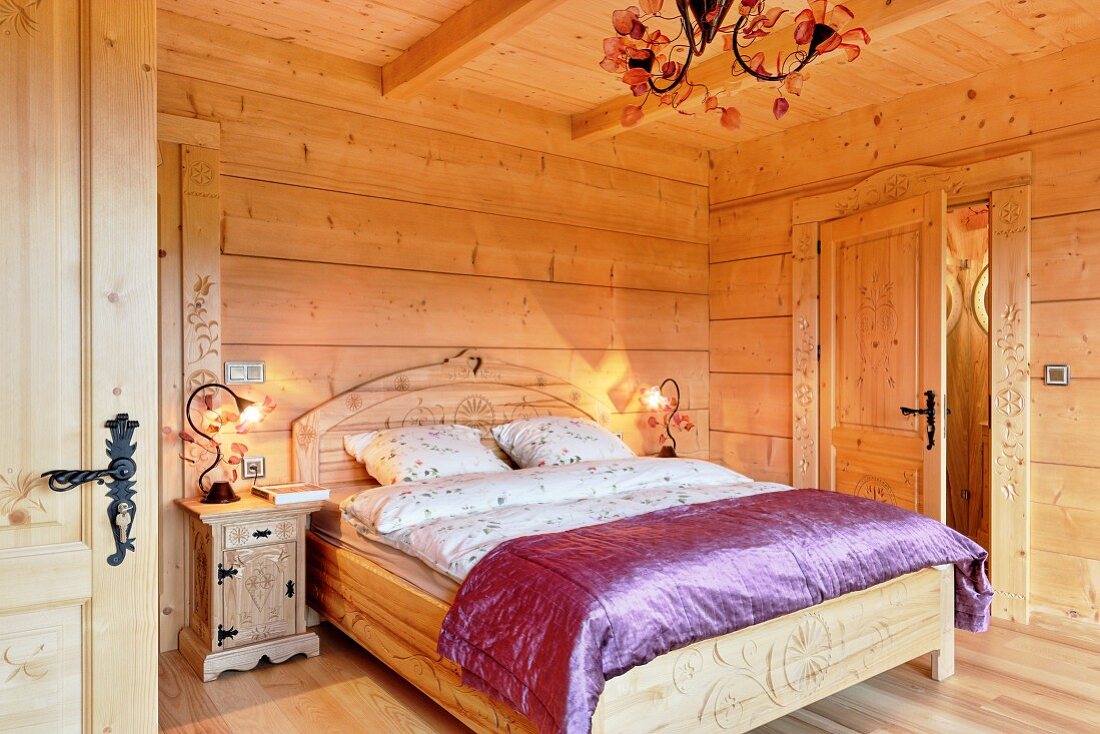 Double bed with curved headboard and purple silk cover in solid wooden house