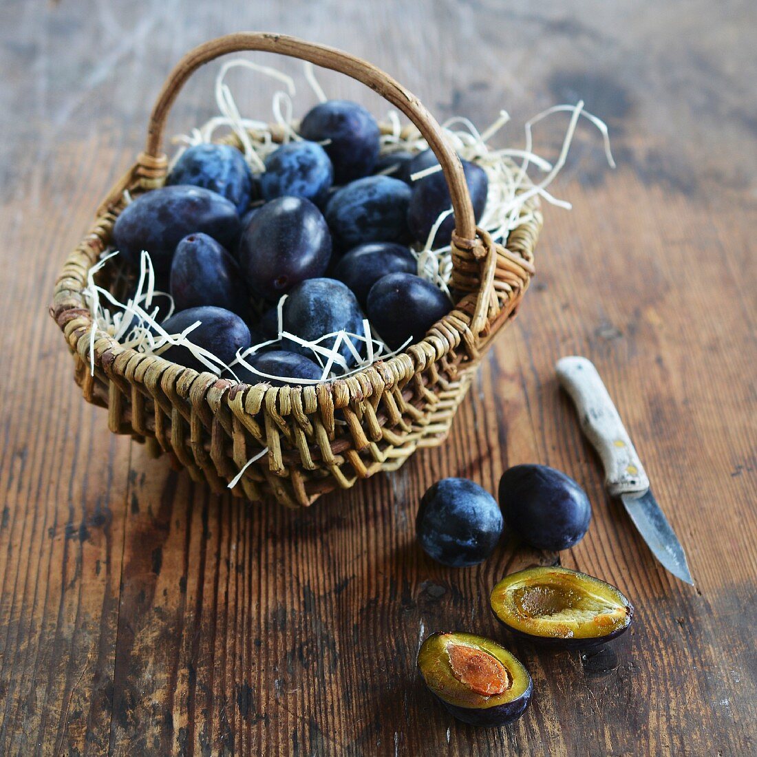 Plums in a rustic basket and next to it