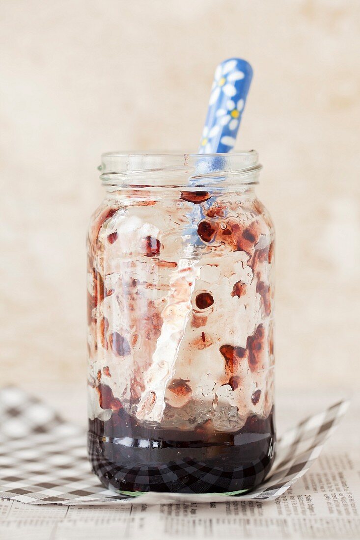 An opened jar of jam with a knife in it