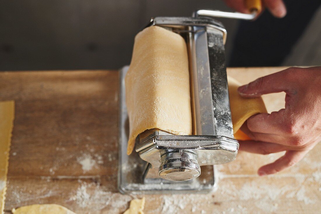 Pasta pastry being passed through a pasta machine